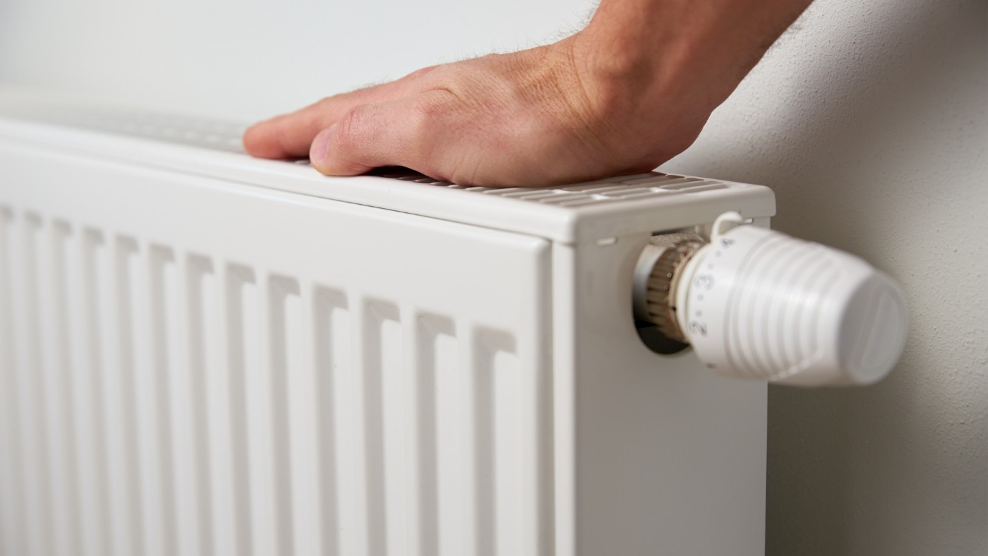 A hand placed on a heater to check if it is working.