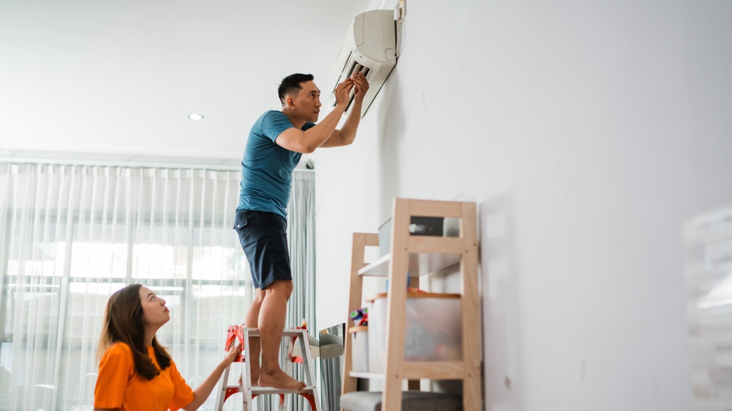 A home owner examines his air conditioning unit to fix it.