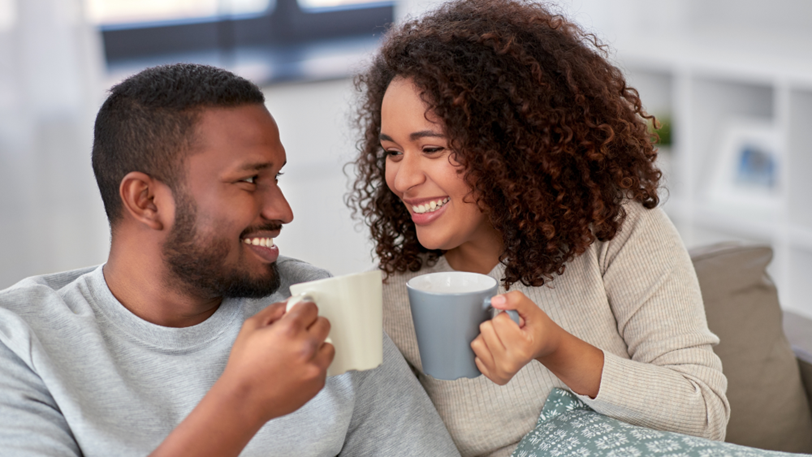 A couple drink from mugs in the comfort of their home during winter.