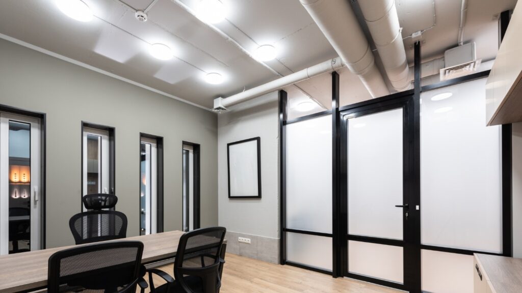 An office space with large HVAC ducts and vents on the ceiling.