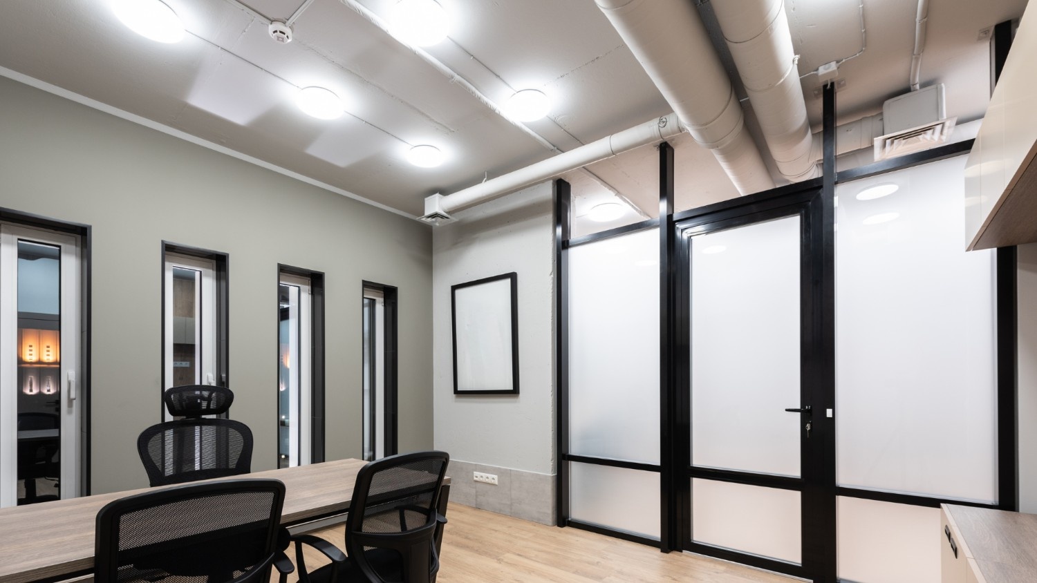 An office space with large HVAC ducts and vents on the ceiling.