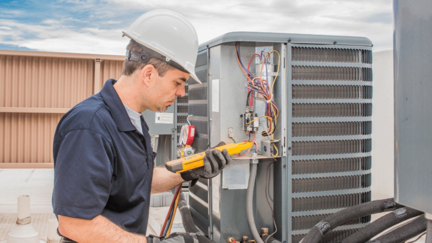 An HVAC technician observes readings on a testing device near a unit.